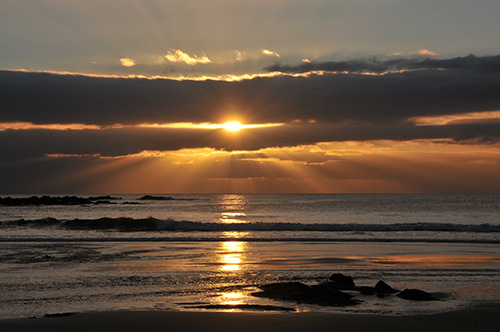 Picture of a sunset with the sun shining through some low clouds