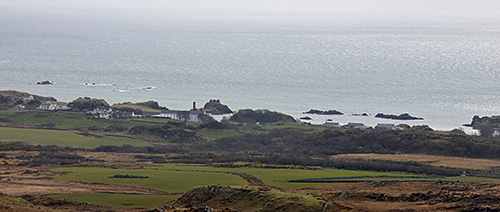 Picture of coastal village with a distillery, seen from coastal hills behind