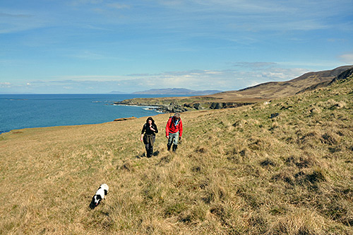 Picture of two walkers and a dog walking along a northern coast