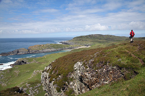 Picture of a man walking on a hill along a dramatic coastline