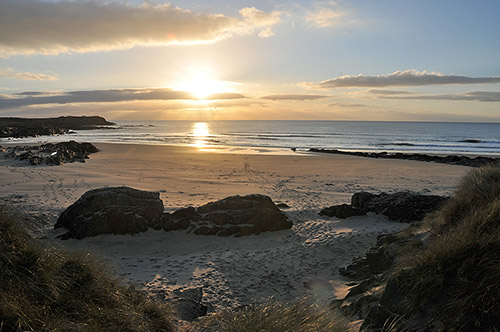 Picture of an October sunset over a bay with a sandy beach