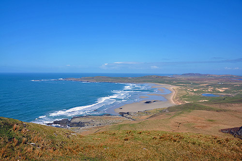 Picture of a view over a bay with a wide sandy beach from a hill overlooking the bay