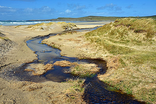 Picture of a burn (river) meandering across a beach