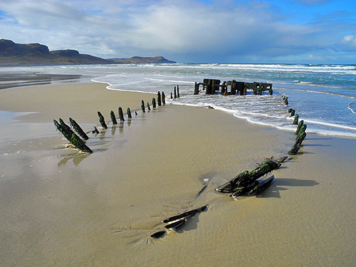 Picture of a wreck on a beach with a wave rolling in