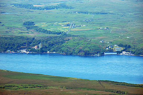 Picture of a view from a hill over a sound to two settlements and a distillery