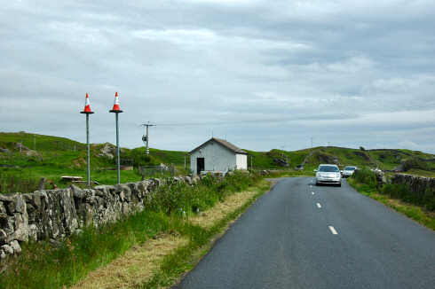 Picture of a road with two poles next to it, traffic cones on the top of the poles